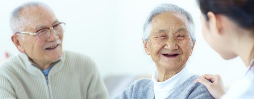 Life Assure Seniors Smiling And Speaking With Caregiver At Home Hero